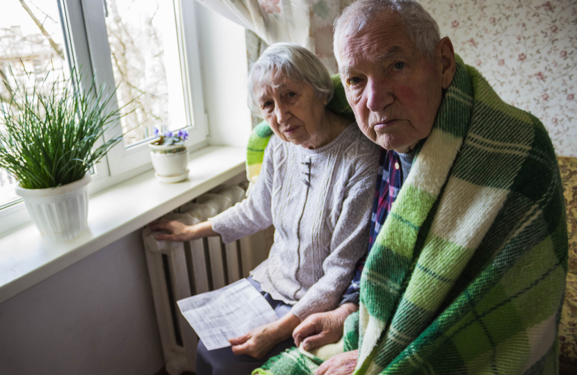 Two older people next to radiator with bill